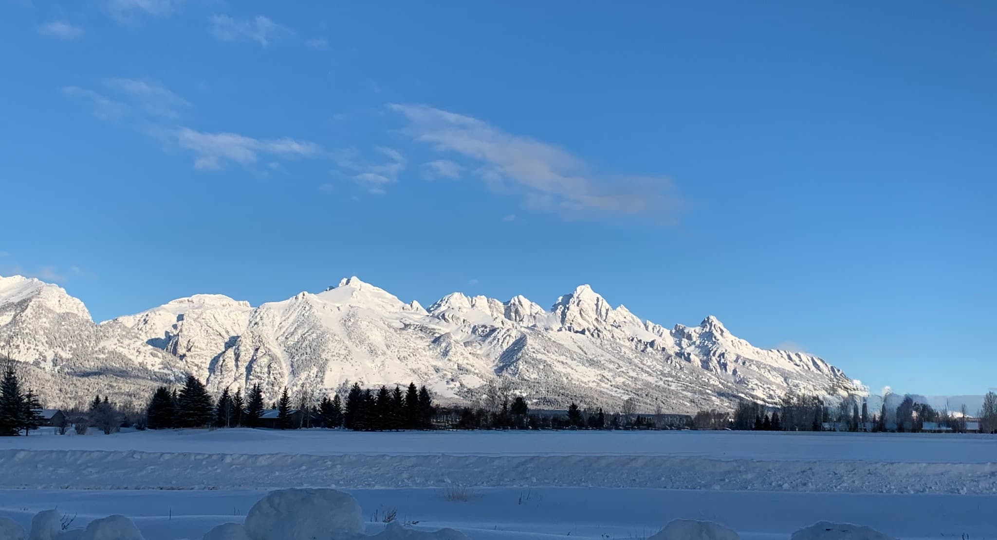 The snow-covered Teton Range beneath a clear blue winter sky